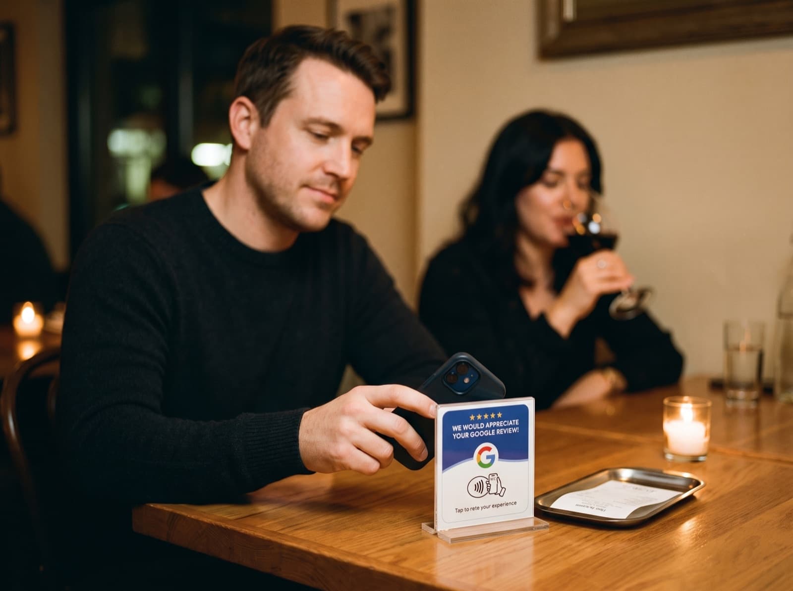 A guest taps their phone against the TapPoint card on the table after dinner